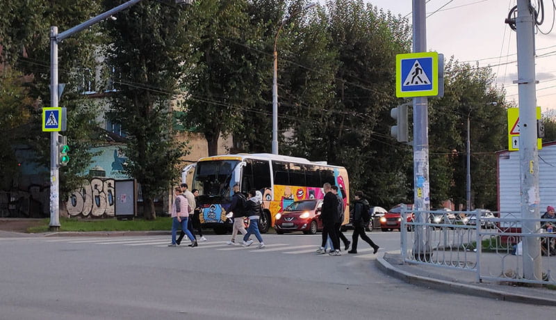 пешеходы переходят по пешеходному переходу перед машинами