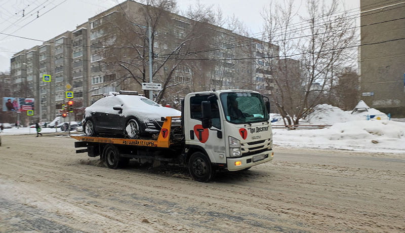 эвакуатор везет машину в снегу