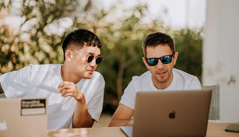 двое мужчин разговаривают и смотрят в ноутбук