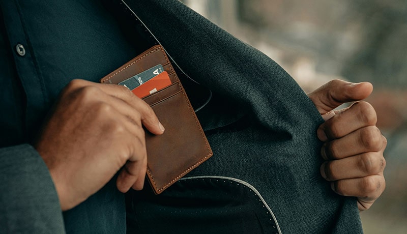 мужчина достает кошелек из внутреннего кармана пиджака