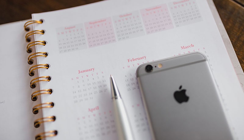 календарь в блокноте, ручка и телефон
