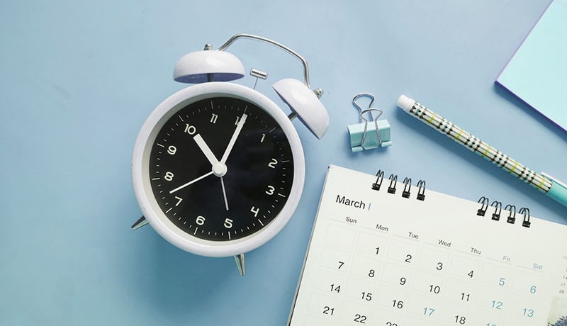 часы, календарь и ручка лежат на столе