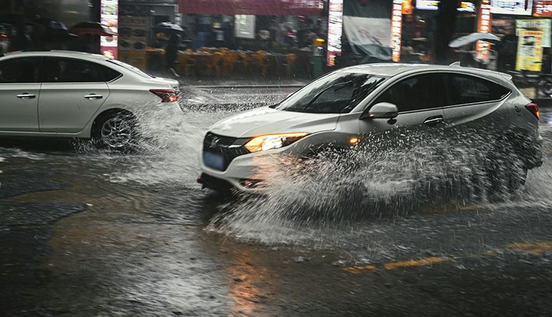 машина едет в дождливую погоду по лужам