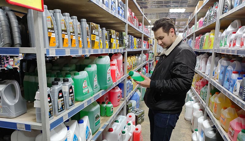 мужчина рассматривает флакон в магазине автотоваров