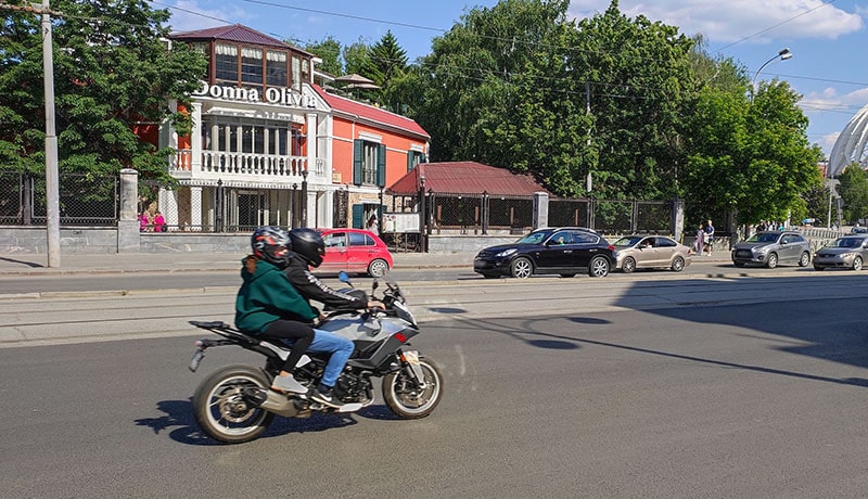 мотоциклист с пассажиром едет по дороге