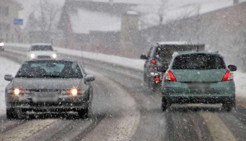 автомобили едут по заснеженной грязной дороге