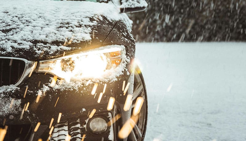 автомобильная фара близким планом в снежную погоду