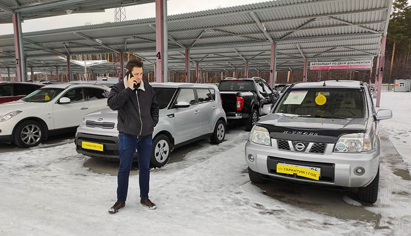 мужчина разговаривает по телефону на авторынке