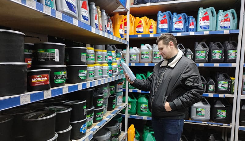 мужчина выбирает тормозную жидкость в магазине